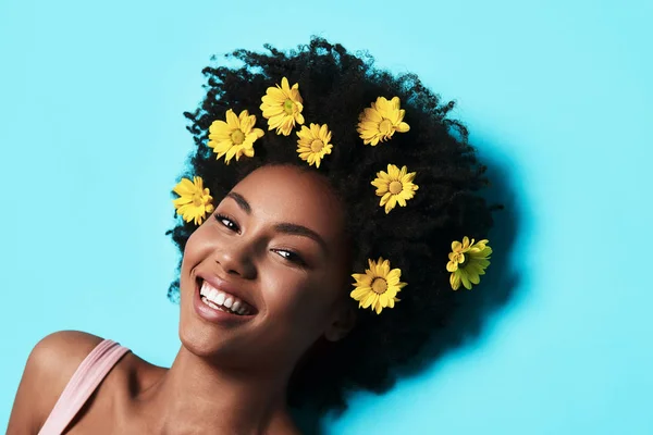 Happy Young African Woman Yellow Flowers Hair Lying Blue Background — Stock Photo, Image