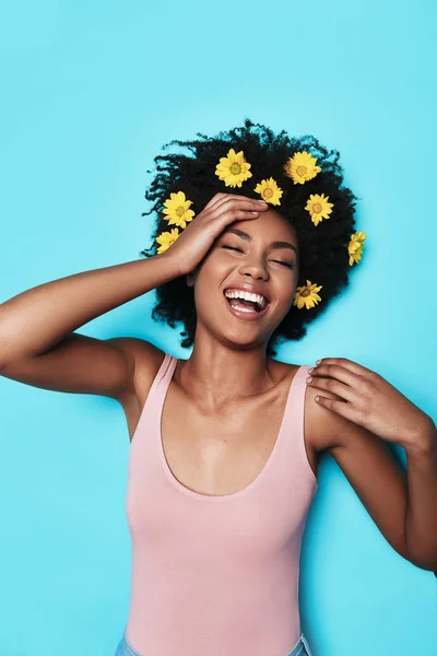 Laughing Young African Woman Lying Blue Background Yellow Flowers Hair — Stock Photo, Image