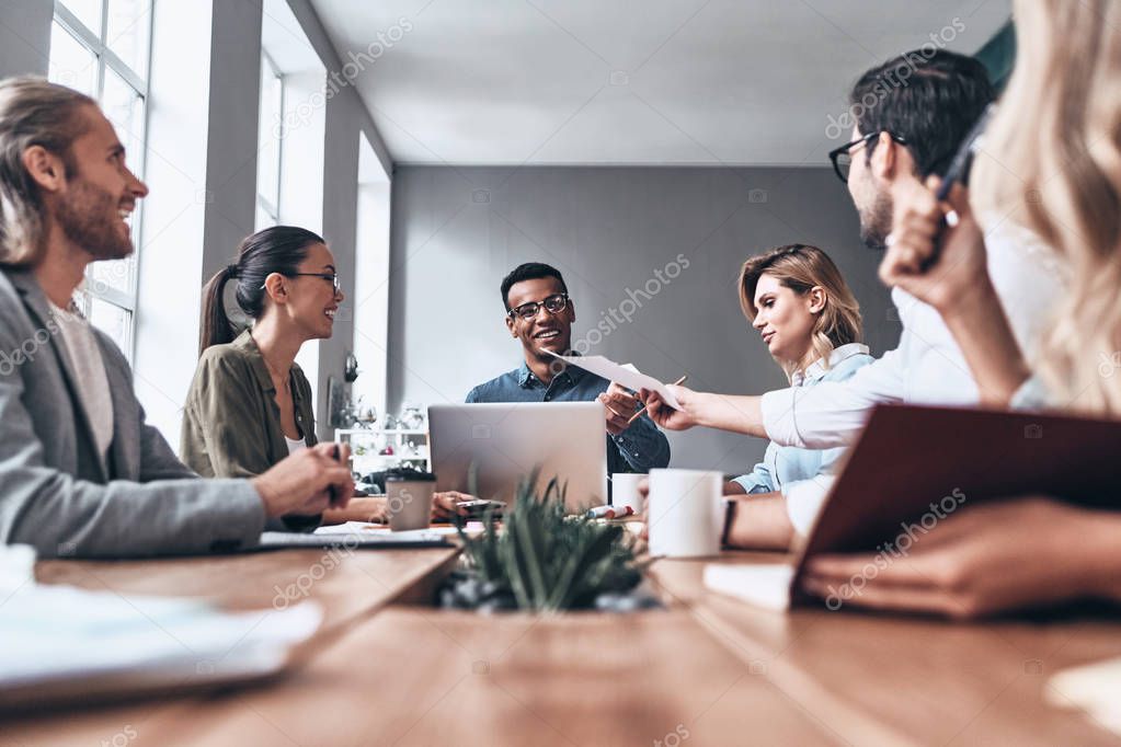 group of happy business colleagues at wooden table in creative modern office studio, 