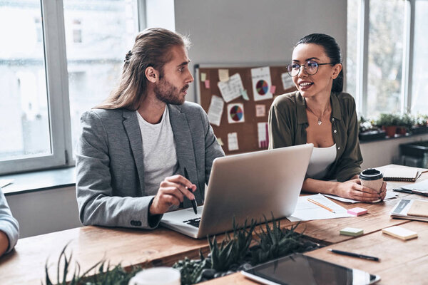 бизнесмен и женщина за деревянным столом с ноутбуком в креативной современной офисной студии
 