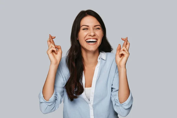 Atractiva Joven Mujer Cruzando Los Dedos Sonriendo Mientras Está Pie —  Fotos de Stock