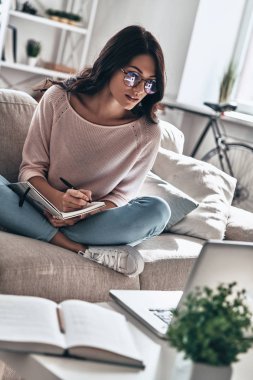 Güzel ve genç birbayan bardaklarda ise evde kanepede oturan ve texbook içinde yazım kalemi ile eğitim 