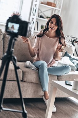 Modern vlogger, güzellik ürünleri tutarak ve sosyal medya video yaparken gülümseyen genç kadın      