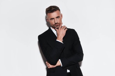 yakışıklı genç adam çeneme el tutmak ve kamera beyaz arka plan karşı dururken bakarak tam takım