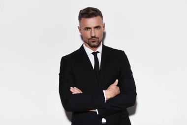 Tam takım geçti ve kamera beyaz arka plan karşı dururken bakarak silah tutmak yakışıklı genç adam