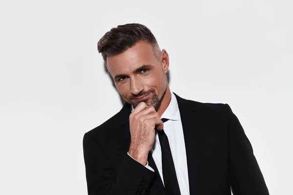 caucasian ethnicity businessman in studio posing on camera with smile and hand on chin