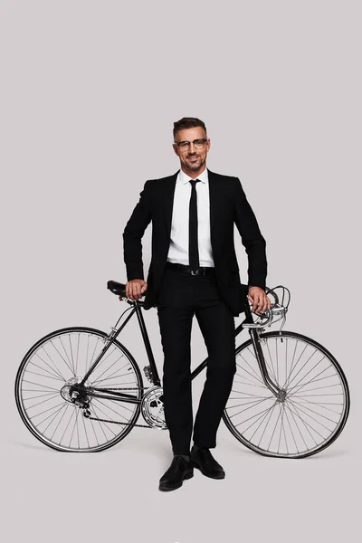 灰色の背景で自転車でフルスーツ立って見ている善人の全長 — ストック写真