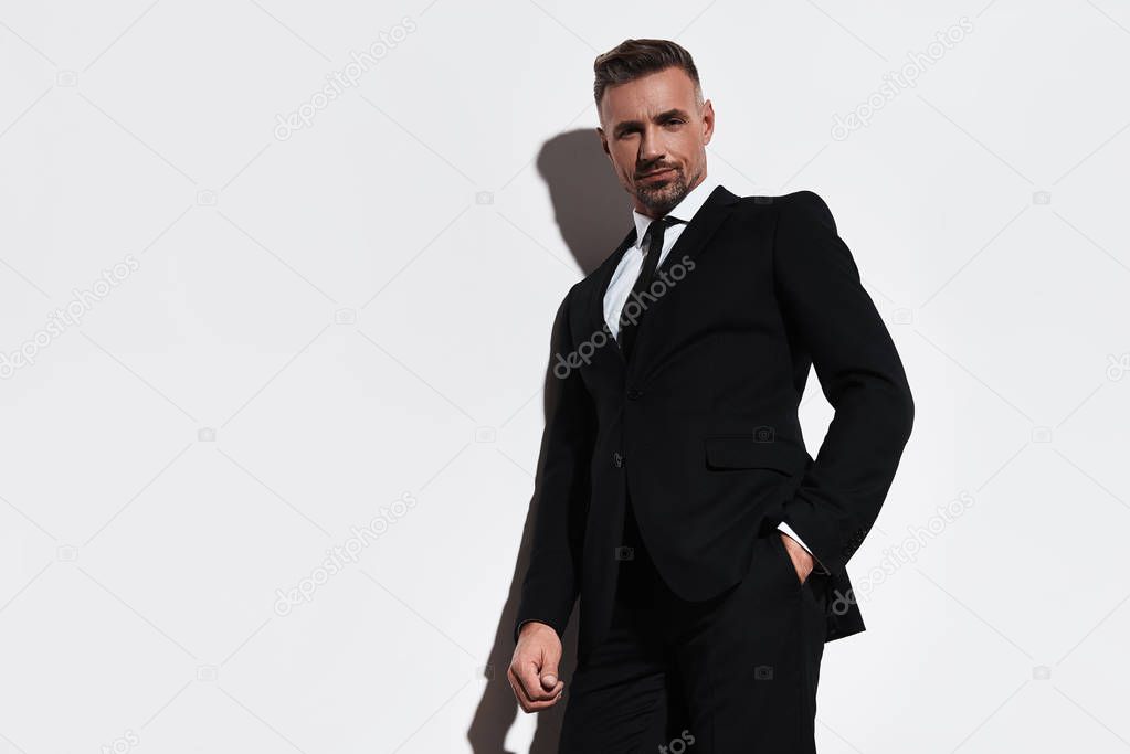 business man standing against white background and  posing on camera, leaning on wall 