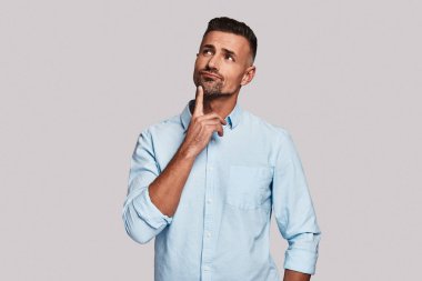 Çene ve gri arka plan karşı dururken ararken el tutmak düşünceli genç adam