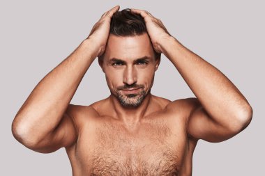 saç ve gri arka plan karşı dururken gülümseyen gömleksiz adam tutan eller