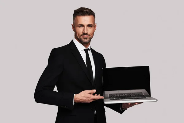 英俊的商务男子与笔记本电脑 站在白色的背景下 显示黑屏 — 图库照片