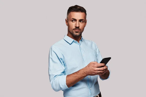 Uomo Abbigliamento Casual Intelligente Utilizzando Suo Smartphone Sorridente Mentre Piedi — Foto Stock