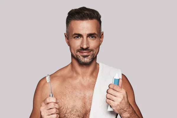 Handsome Young Man Holding Toothbrush Toothpaste While Standing Grey Background — Stock Photo, Image