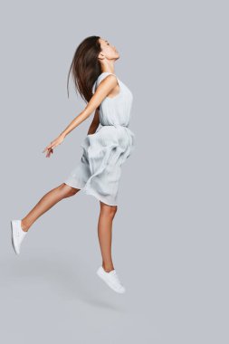 Güzel genç Asyalı kadın karşı gri arka plan asılı tam uzunlukta