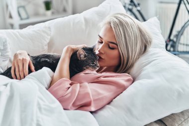 Evde yatakta yalan sırasında onu kedi tutan çekici genç kadın     