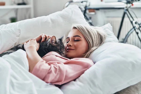 Приваблива Молода Жінка Тримає Свого Кота Посміхається Лежачи Ліжку Вдома — стокове фото