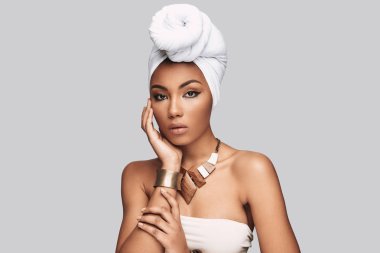 Kendinden emin ve güzel. Çekici Afrikalı kadın kamera gri arka plan karşı dururken bakarak türban