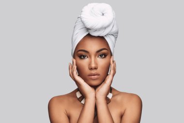 Afrika geleneği. Çekici Afrikalı kadın kamera gri arka plan karşı dururken bakarak türban