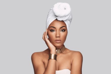 Afrika tarzı. Çekici Afrikalı kadın kamera gri arka plan karşı dururken bakarak türban