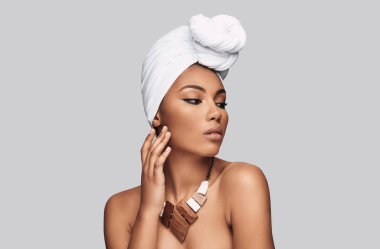 Afrika Güzeli. Çekici genç Afrikalı kadın türban uzak duran gri bir arka plana dayanır arıyor.