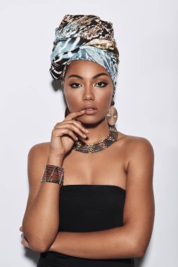 Sakin ve rahat. Çekici Afrikalı kadın kamera gri arka plan karşı dururken bakarak türban