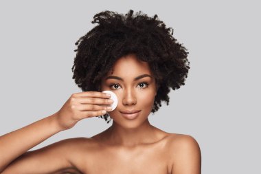 Pampering. Çekici genç Afrikalı kadın uygulanan temizlik sünger ve gri arka plan karşı dururken gülümseyen