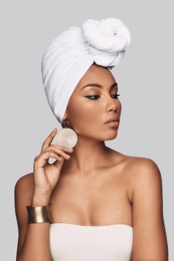 Tehlikeli derecede güzel. Küpe ayarlama ve uzak duran gri arka planı arıyorum türban çekici genç Afrika kadın