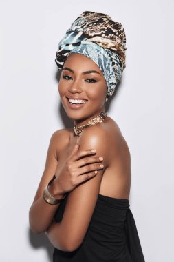 O senin kalbini eriyecek. Kameraya bakarak ve gri arka plan karşı dururken gülümseyen türban çekici genç Afrika kadın