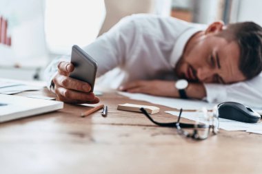 masanın üzerinde yatan ve cep telefonu tarama yorgun işadamı 