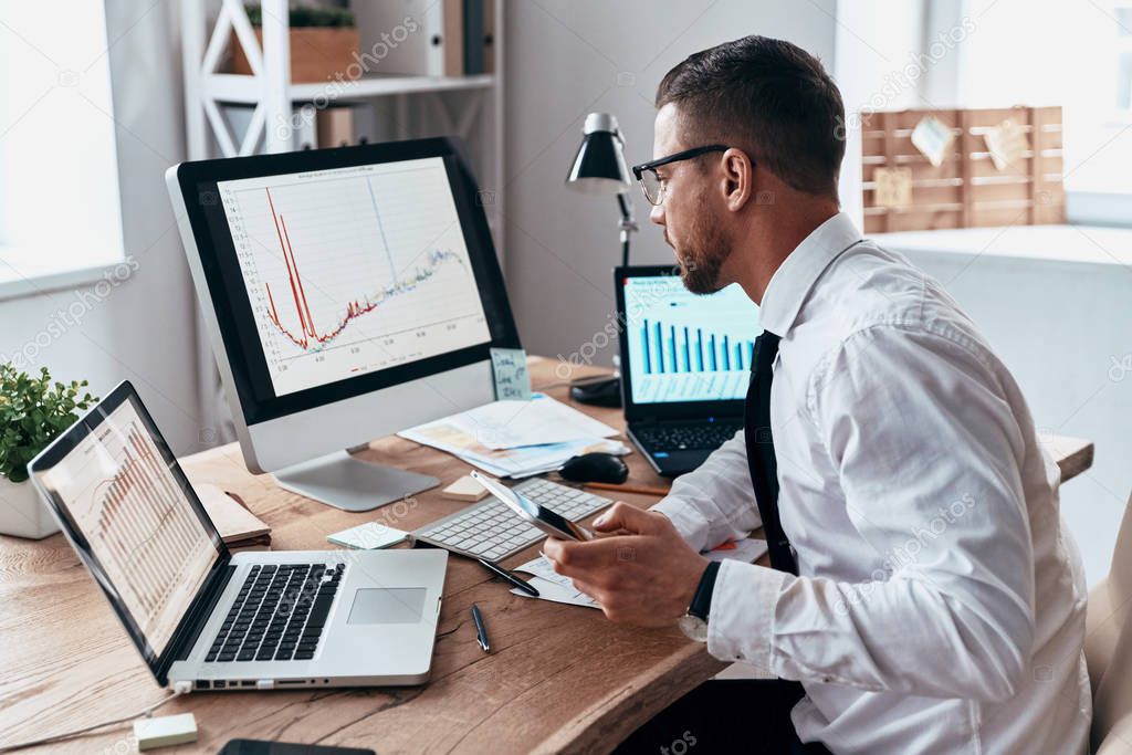 businessman at office desk with digital table, computer and laptops working 