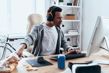 evde vakit geçirmek ve patates cipsi yemek sırasında bilgisayar kullanan adam