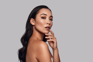 Kamera gri arka plan karşı dururken bakarak duygu doğal, güzel genç bir kadın