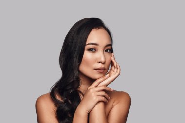 Zevk onun güzellik, güzel genç kadın kamera gri arka plan karşı dururken bakarak