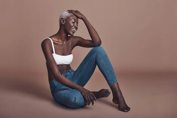 Kahverengi Arka Planı Oturma Denim Jeans Ile Üst Giyiyor Mutlu — Stok fotoğraf
