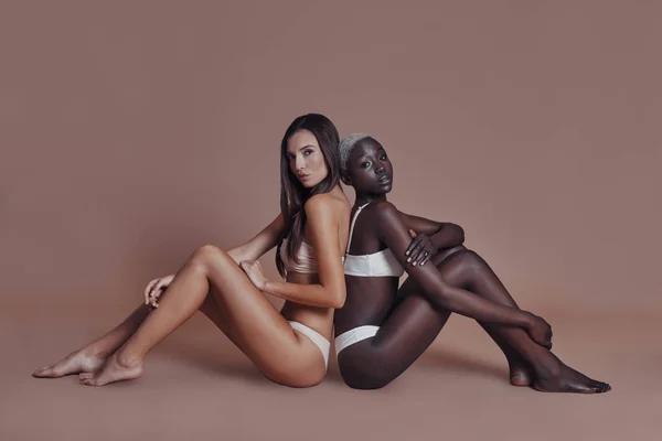 有吸引力的混血妇女在内衣坐在地板上的棕色背景 — 图库照片