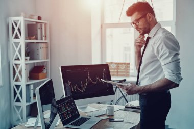 Ofiste çalışırken dijital tablet kullanarak verileri analiz resmi kıyafeti düşünceli genç işadamı