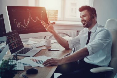 Genç işadamı kulaklık müşteriyle konuşurken ve gülümsüyor ofiste otururken