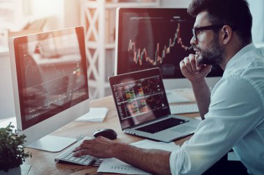 Strateji, düşünceli genç iş adamı resmi kıyafeti ofiste otururken bilgisayar kullanarak verileri analiz analiz