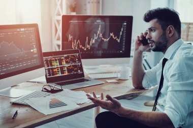 Strateji, ofiste otururken akıllı telefonda konuşurken resmi kıyafeti içinde genç işadamı tartışıyor