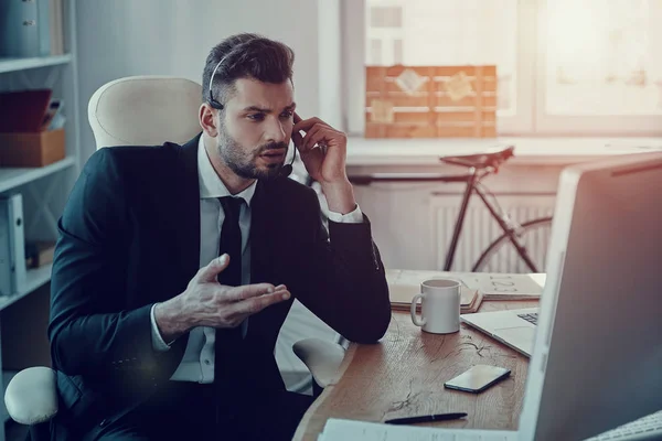 Jeune Homme Sérieux Dans Casque Parler Avec Client Tout Étant — Photo