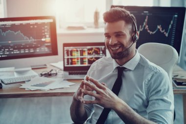 Genç ve akıllı işadamı kulaklık müşteriyle konuşurken ve gülümsüyor ofiste otururken