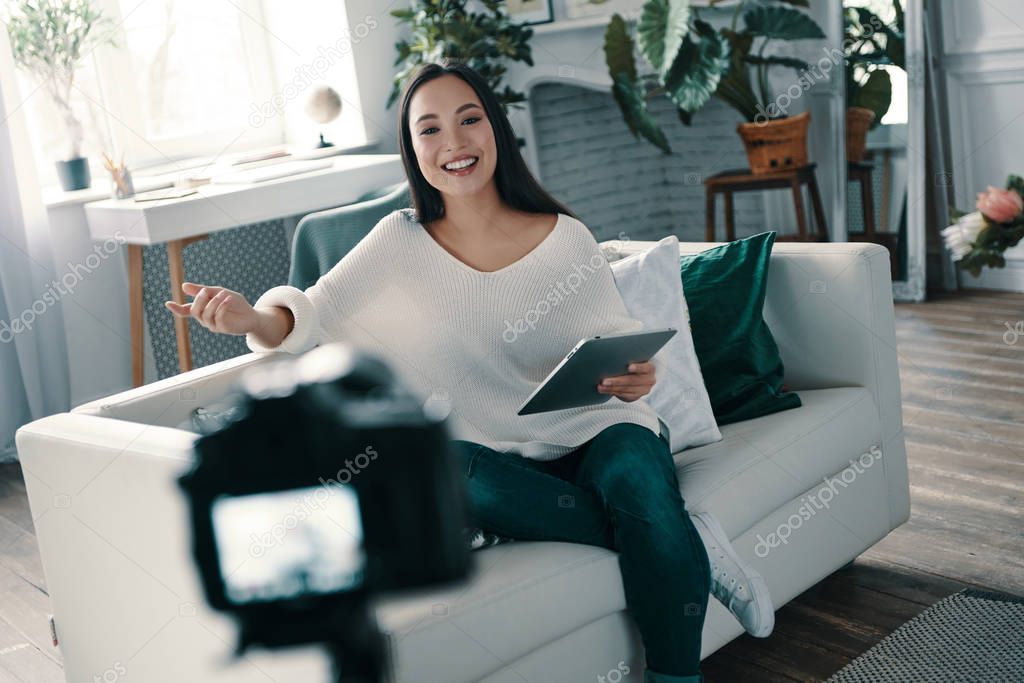 Beautiful influencer. Attractive young woman gesturing and smiling while making new video for her blog                 