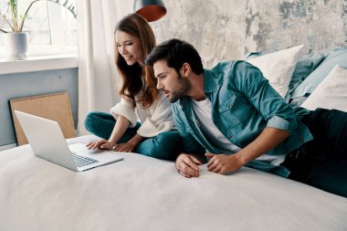 evde yatakta zaman harcarken bilgisayar kullanarak güzel genç çift 