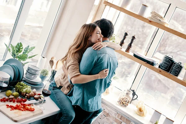 Счастливая Молодая Пара Обнимается Кухонным Столом — стоковое фото