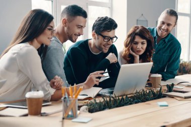 Başka bir iş günü. Yaratıcı ofiste çalışırken modern teknolojileri kullanarak akıllı gündelik giyim genç modern insanların grubu