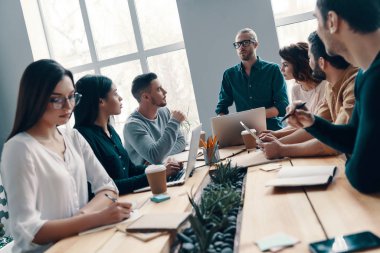 Beyin fırtınası birlikte. Yaratıcı ofiste çalışırken bir şeyler tartışıyor akıllı rahat giyim genç modern insanların Grubu        