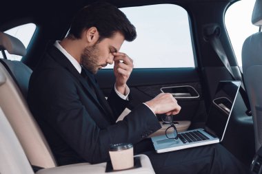 Overworked. Arabada otururken burun masaj tam takım sinirli genç adam         