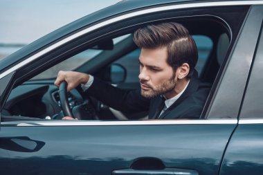 Trafiğe takıldım. Tam takım elbiseli yakışıklı genç adam bir araba sürerken düz görünümlü    