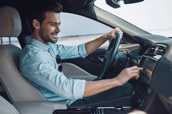 享受他的驾驶 英俊的年轻人在智能休闲装微笑 而驾驶状态车 — 图库照片