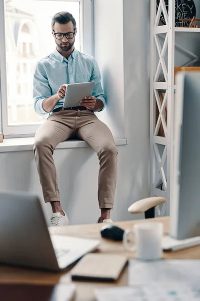 Młody Nowoczesny Biznesmen Pracujący Tablecie Cyfrowym Siedząc Parapecie Biurze — Zdjęcie stockowe